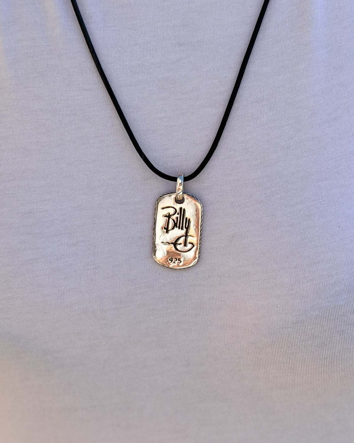 Woman wearing the Have Mercy pendant on a black leather cord over a white t-shirt, back view with Billy G signature and .925 stamp